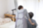 Nurse in an apron pushing an elderly patient in his wheelchair