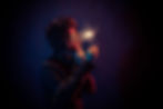 Young man in the dark wearing sunglasses and waving a lit sparkler. The photograph captures the light movement in a trail