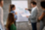 Male entrepreneur and his colleague developing new strategy and talking about new sustainability ideas in front of whiteboard.