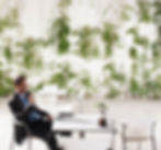 Middle aged man relaxing at a table while enjoying the indoor green environment of his office