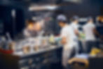 Image of busy restaurant kitchen with the female Chef preparing the menu